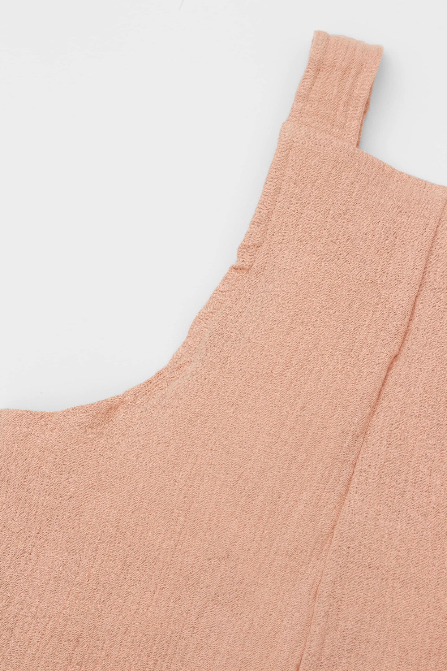Organic cotton short leg overall in clay muslin. Loose fit and buttoned straps and cargo pockets. Back detail