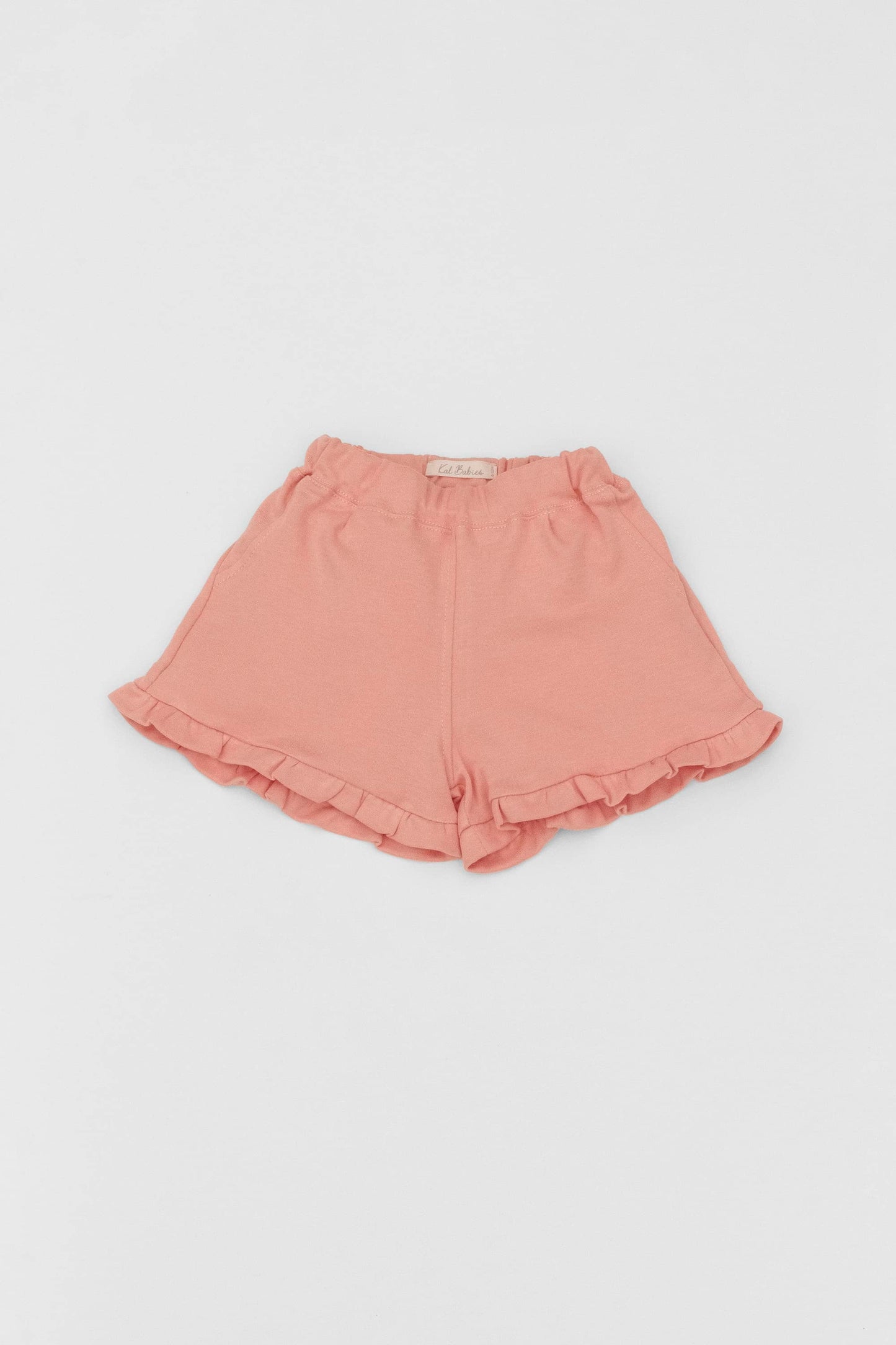 Organic pima cotton shorts with ruffle hem, elasticized waist and fake pockets. soft melon. Front view