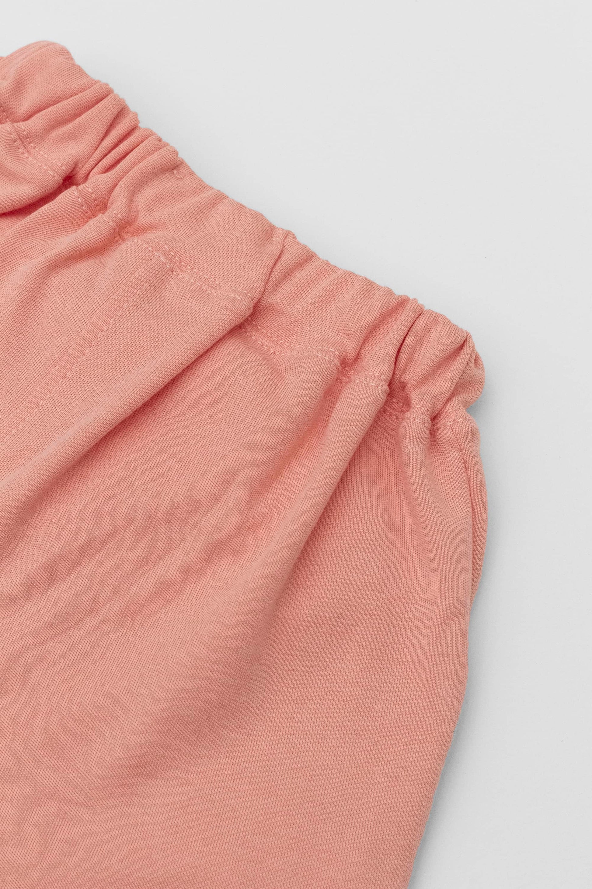 Organic pima cotton shorts with ruffle hem, elasticized waist and fake pockets. soft melon. Back detail