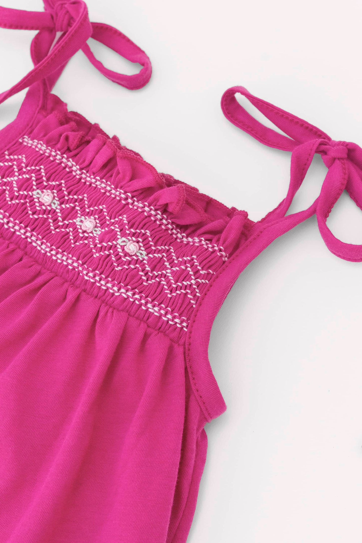 Smocked very berry organic romper with straps and embroidery. Embroidery detail