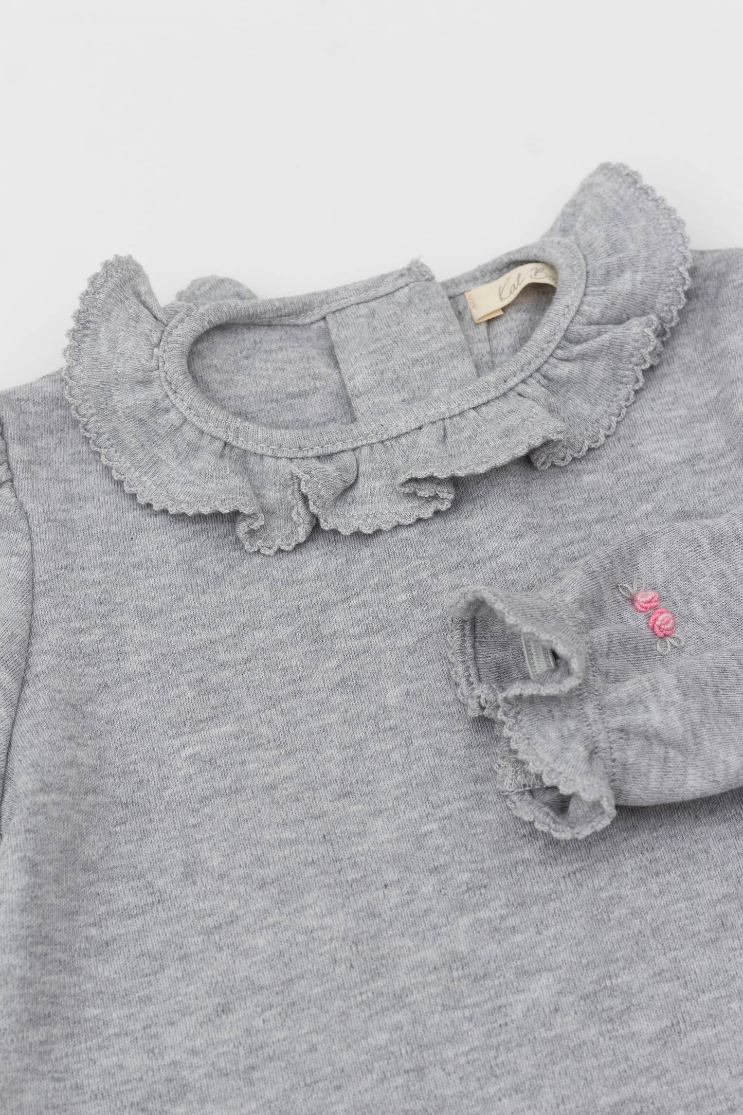 Bodysuit with ruffle collar and and long puff sleeves. Floral embroidery on sleeves. Snaps inseam. Back button closure. Heather grey color.  Embroidery detail