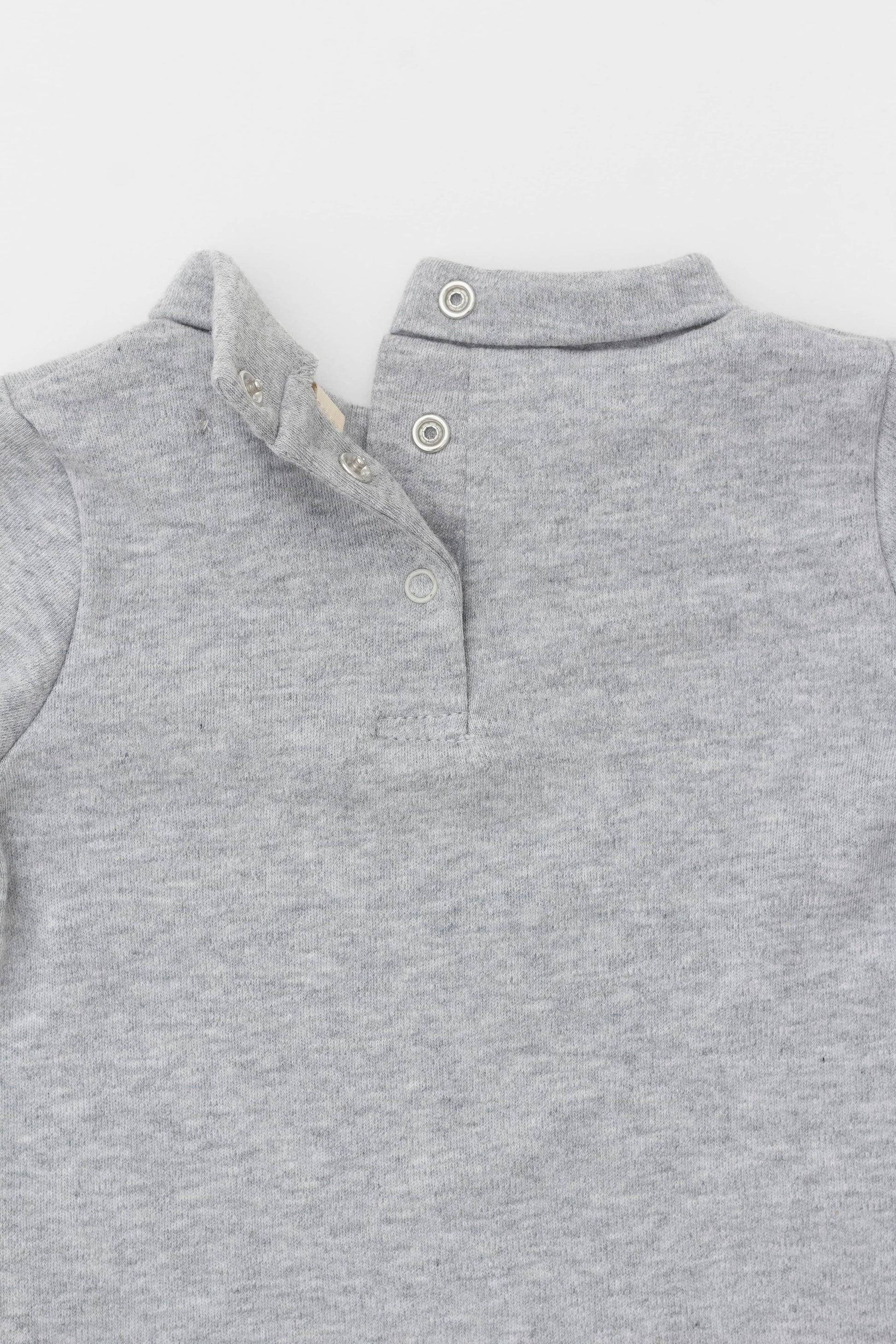 Long sleeve turtleneck bodysuit. Back opening. Snaps inseam. Embroidery detail on sleeve. Heather grey. Opening detail view