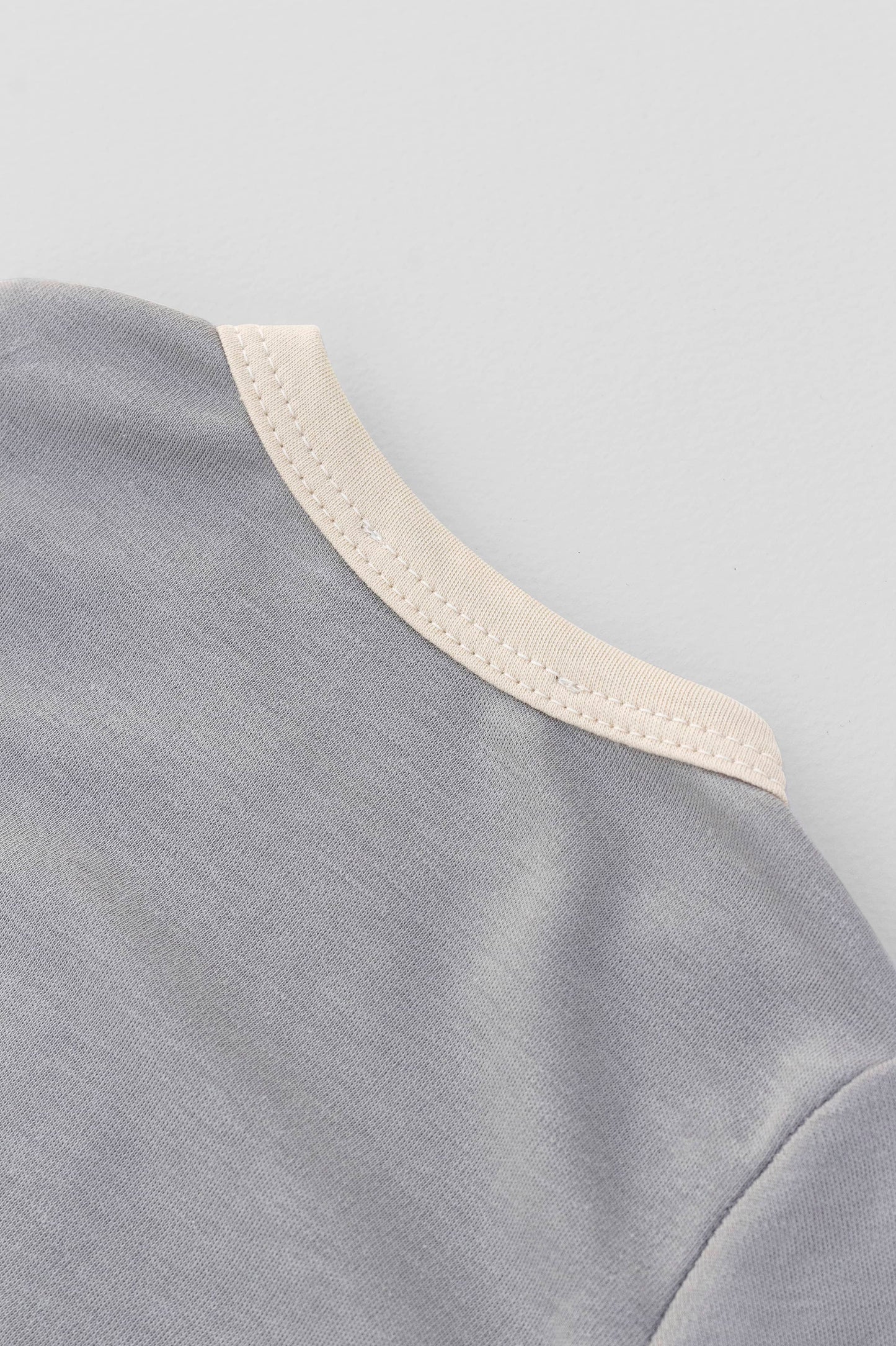 Long sleeve crewneck top with buttons at shoulder. Printed penguin with beanie appliqué. Grey/natural organic pima cotton. Back neckline  view