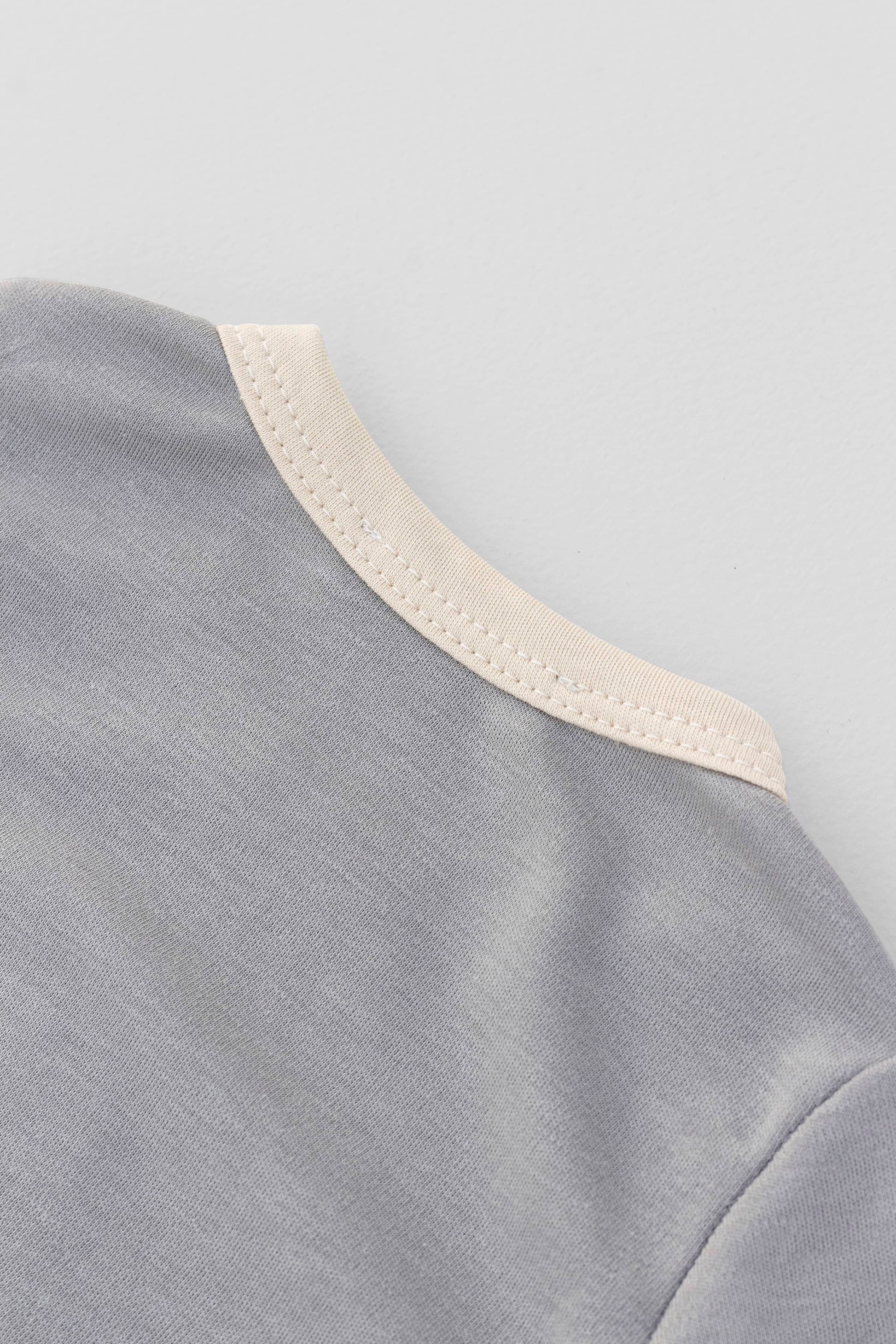Long sleeve crewneck top with buttons at shoulder. Printed penguin with beanie appliqué. Grey/natural organic pima cotton. Back neckline  view