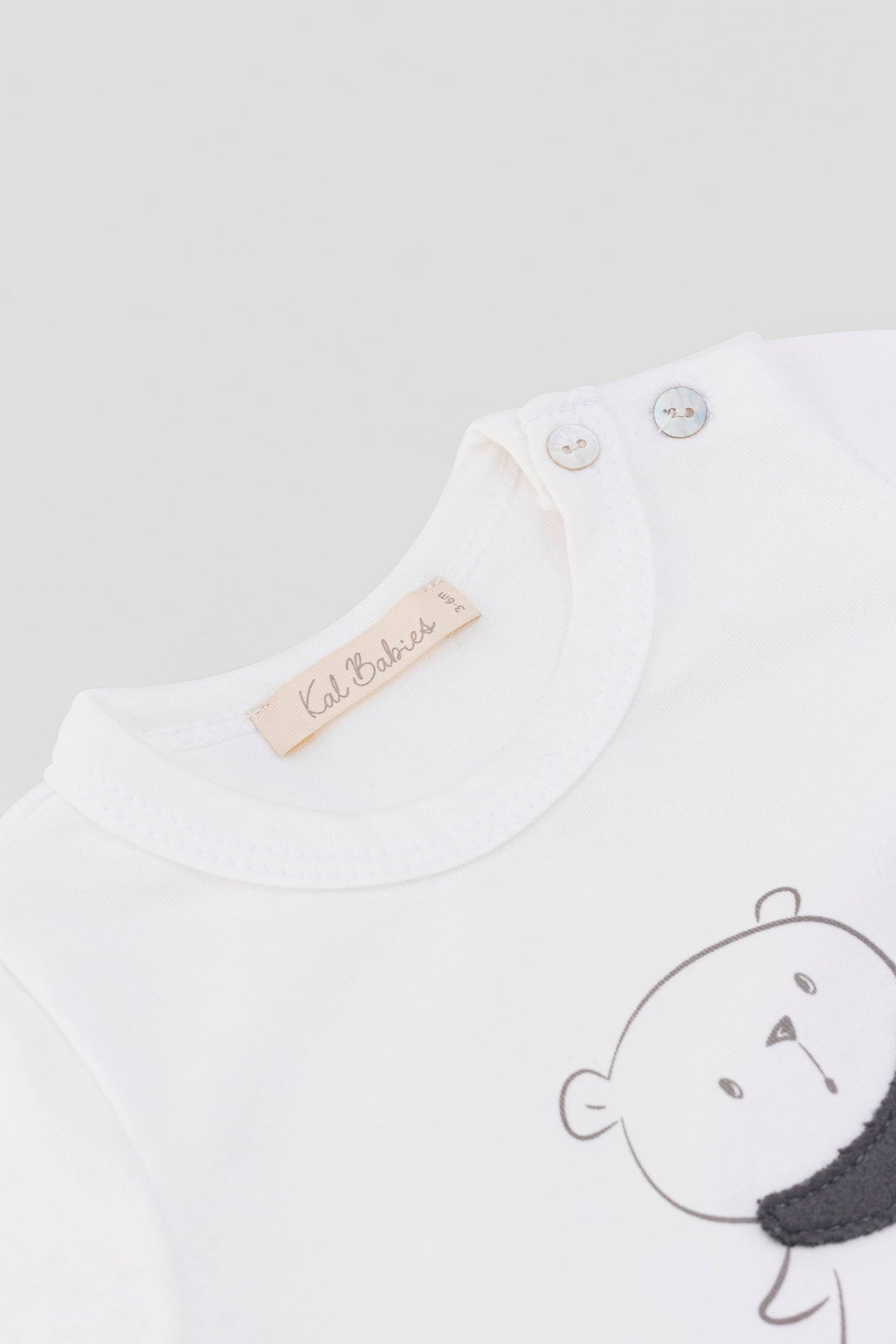 Long sleeve crewneck top with buttons at shoulder. Printed bear with scarf appliqué. Eco white organic pima cotton. Necklineview