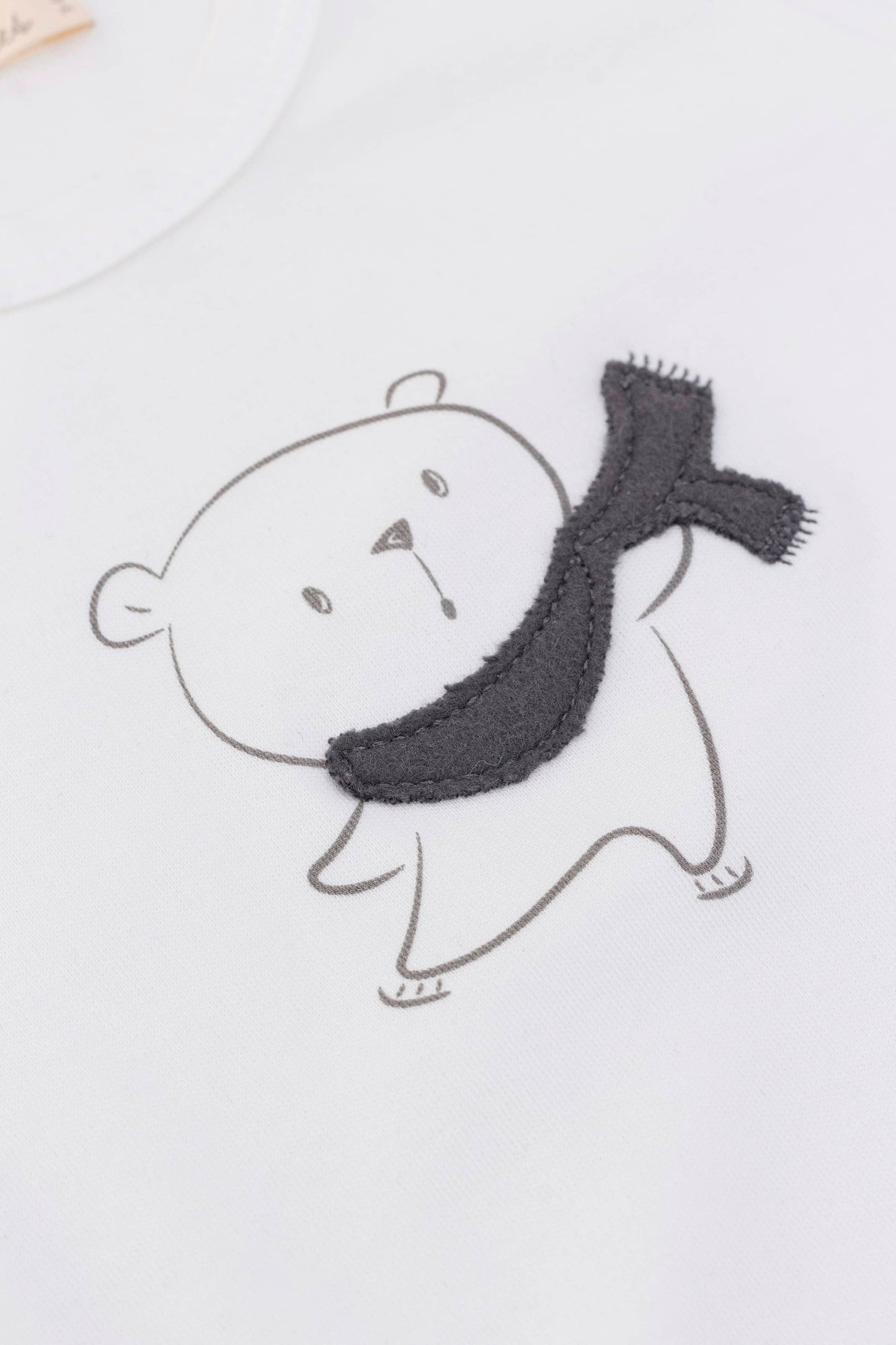 Long sleeve crewneck top with buttons at shoulder. Eco white organic pima cotton. Printed bear with scarf appliqué view