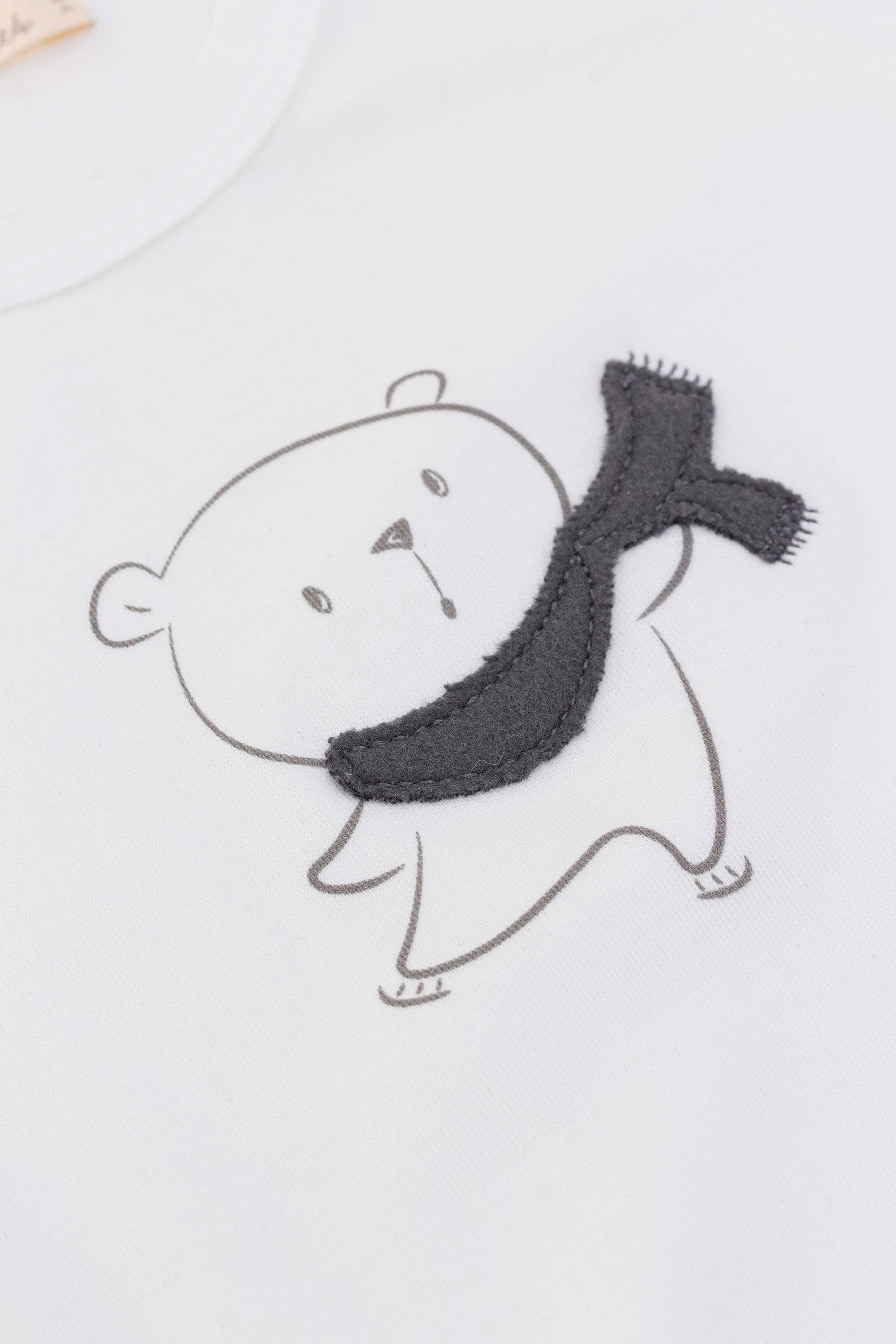 Long sleeve crewneck top with buttons at shoulder. Eco white organic pima cotton. Printed bear with scarf appliqué view