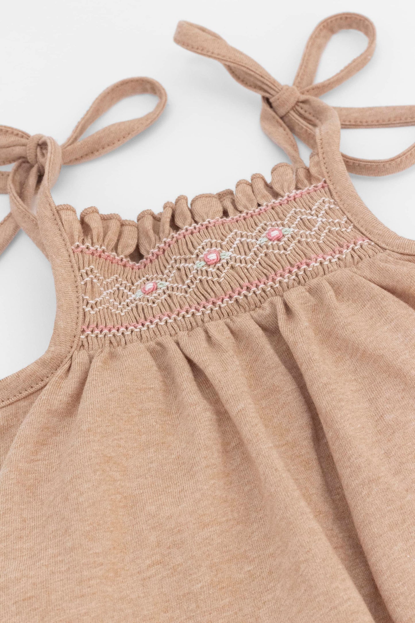 Smocked caramel organic romper with straps and embroidery. Front view detail